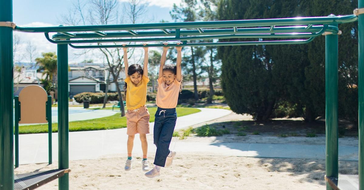 Two kids in Jackalo clothing on monkey bars