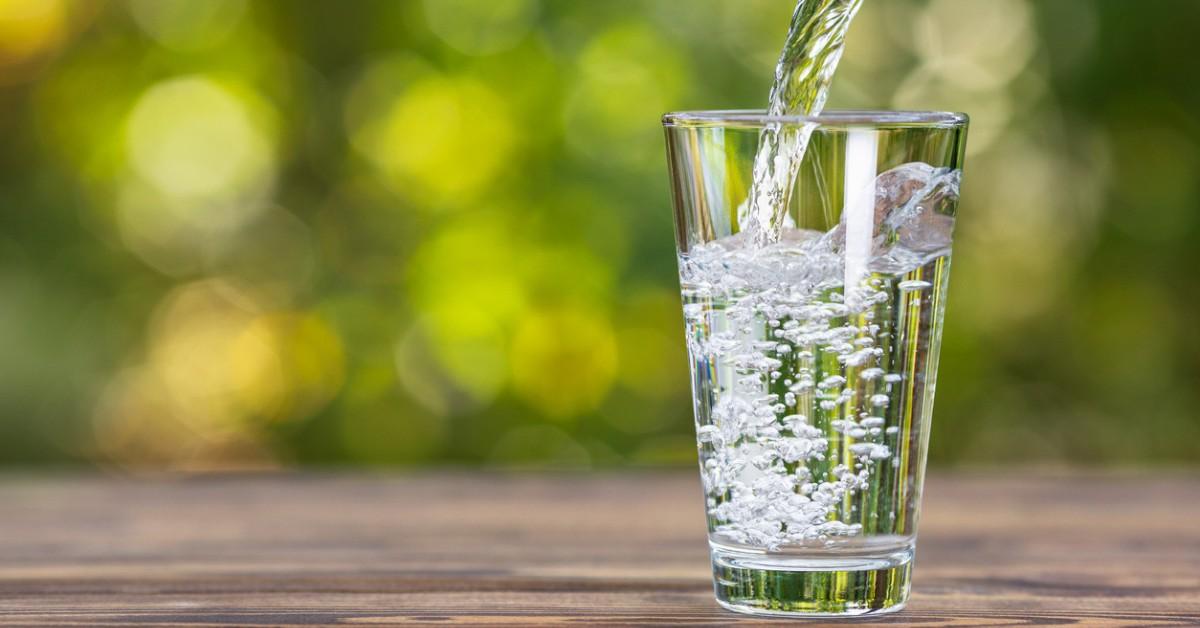 A glass is filled with water, creating bubbles as it's poured