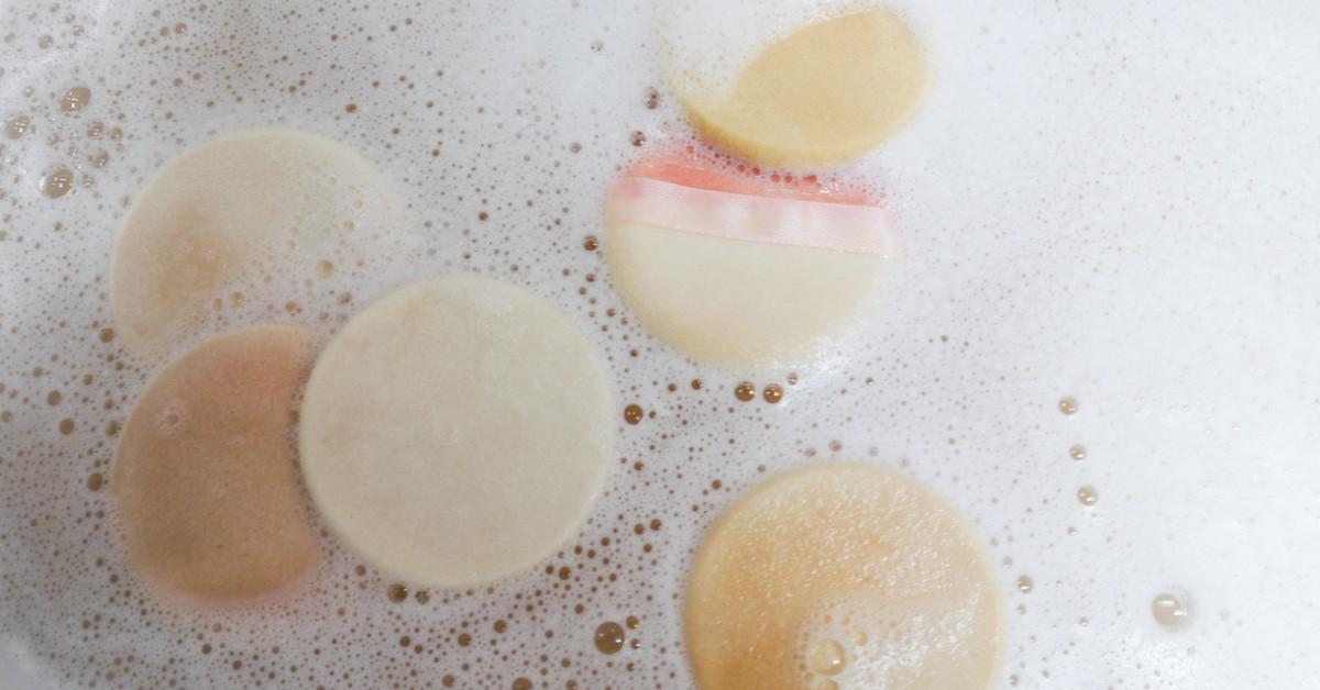 makeup sponges soak in a bowl of sudsy water for cleaning