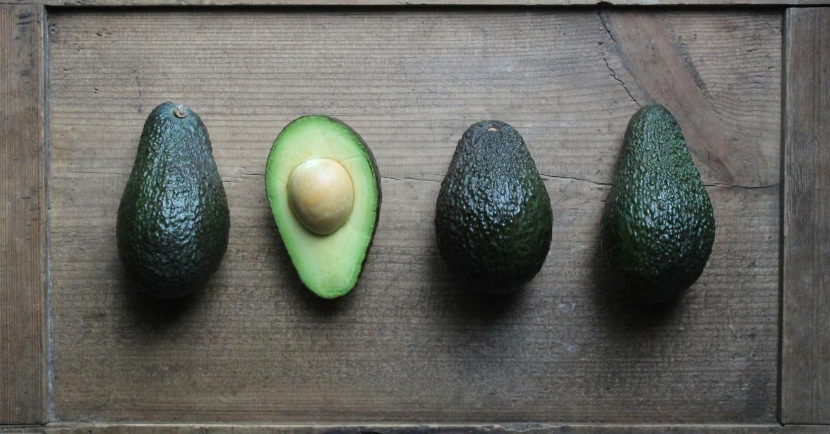 A row of rip avocados sit on a cutting board waiting to be sliced