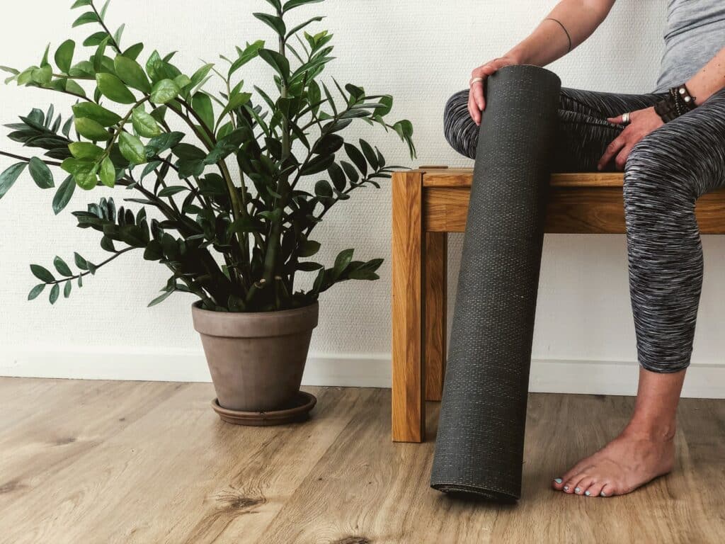 woman sitting on a bench with the best yoga mat for hot yoga